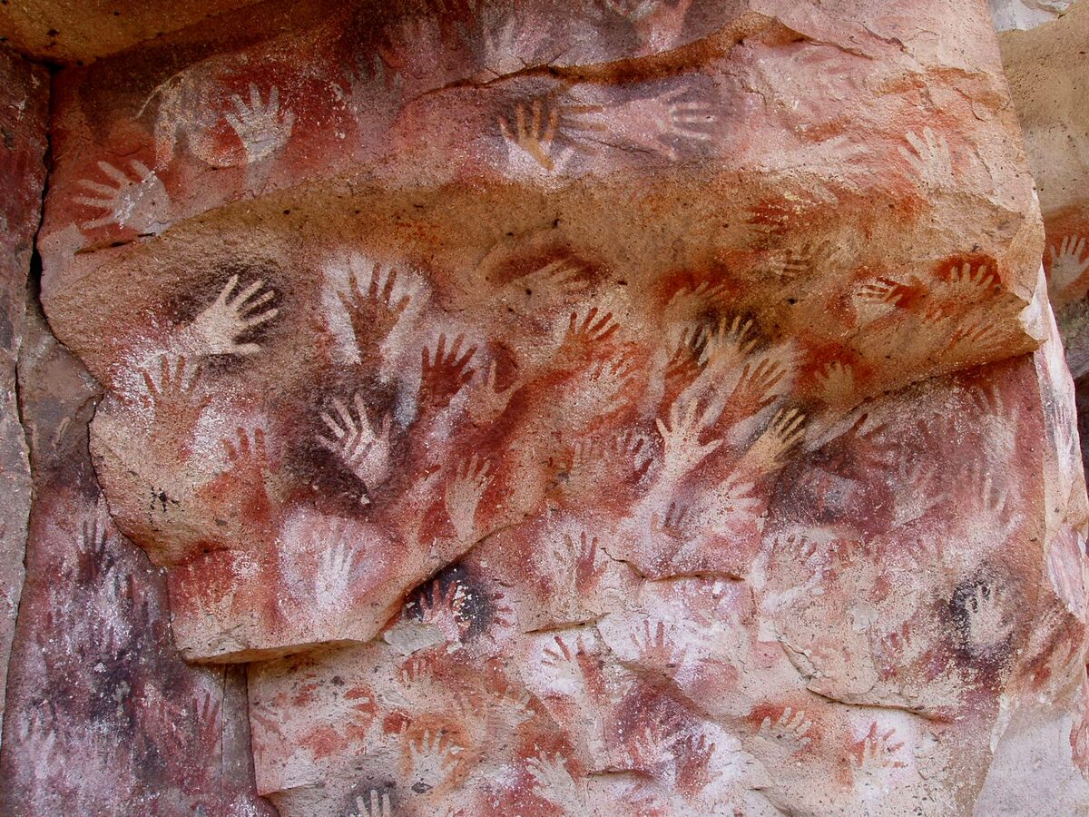 Negative hands painted in ochre on a cave wall