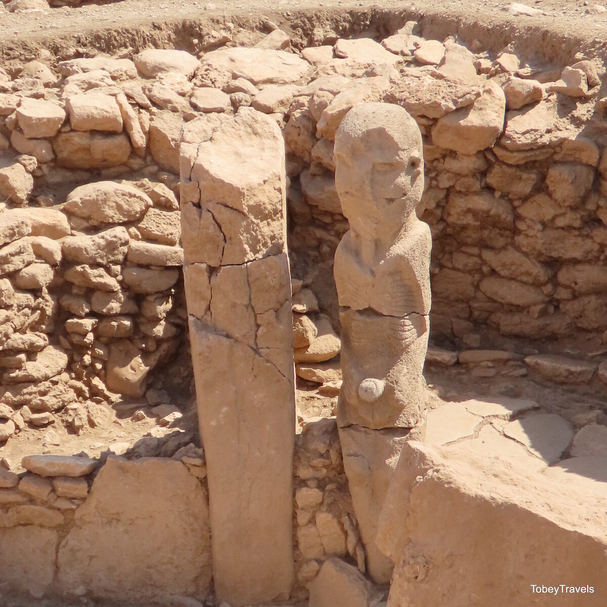 Enclos de Karahan Tepe avec une pierre percée et une statue phallique dressée, illustrant le dispositif rituel propre au site.